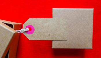 Cardboard boxes with a tag. Brown packing box with blank label and copy space on red backdrop photo