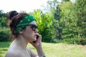 Serious stressed girl speaking on cellphone in park. Frowning young woman in casual calling on mobile phone, listening and staring into distance. Serious phone talk concept photo