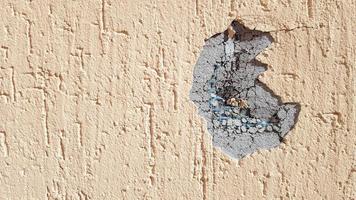 dent on a yellow concrete wall. Hole in the wall with foam insulation. Crack on the yellow wall with decorative putty photo