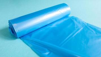 One roll of plastic garbage bags in blue on a blue background. Bags that are designed to accommodate garbage in them and used at home and placed in various garbage containers. photo