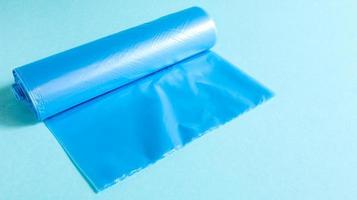 One roll of plastic garbage bags in blue on a blue background. Bags that are designed to accommodate garbage in them and used at home and placed in various garbage containers. photo