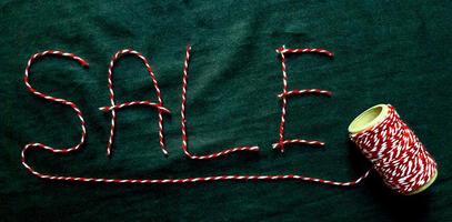 Sale, discount word made of red thread with a spool on a black background. Background, holiday concept. Black Friday - International Day of Shopping, Promotions, Discounts, Sales. photo