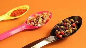 Various spices in plastic spoons on a brown background. Copy space. A mixture of peppers, red smoked paprika, seasoning twelve vegetables. photo