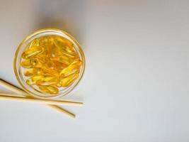 Fish oil capsules on a saucer with chopsticks. Bunch of vitamin omega 3 pills on a white background. Close-up, top view, high resolution product. Metabolism in the body. Body calcium. photo