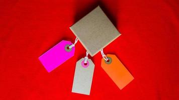 Cardboard boxes with a tag. Brown packing box with blank label and copy space on red backdrop photo