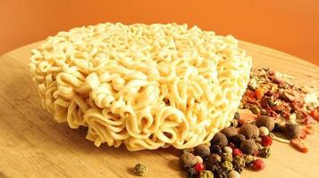 circle of instant noodles with raw spices on a plain brown background. Sprinkle dry Chinese or Korean vermicelli with salt and spices before pouring boiling water. pasta and flavors included photo