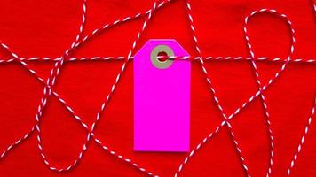 A purple tag on a red rope lies on a red background. Copy space, place for text, flat lay. photo