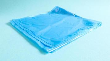 One torn plastic garbage bag in blue on a blue background. A bag that is designed to accommodate garbage in it and is used at home and placed in various garbage containers. photo