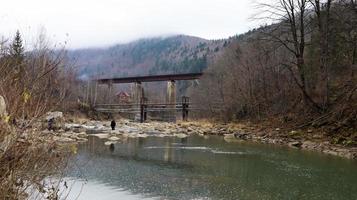 View of the railway bridge over the Prut river. A small town or village of Yaremche among the Carpathians on an autumn afternoon. Ukraine, Yaremcha - November 20, 2019. photo