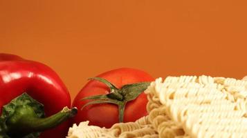 Instant noodles with king mushrooms, seasonings, soy sauce, peppers, green onions, tomatoes. Vegetable fast vegetarian soup. The process of cooking Asian food on the table. Vermicelli, spaghetti photo