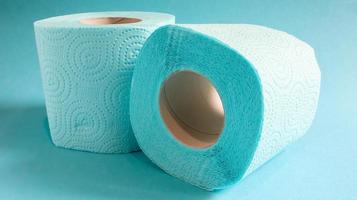 Blue roll of modern toilet paper on a blue background. A paper product on a cardboard sleeve, used for sanitary purposes from cellulose with cutouts for easy tearing. Embossed drawing photo