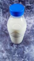 A plastic bottle of fresh regular milk on a dark gray marbled or concrete background. Close-up front view. World milk day concept. Nutrient fluid. Vertical photography. photo