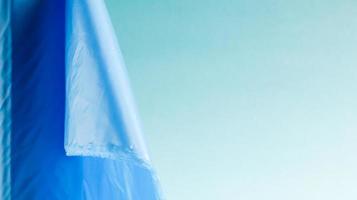 One roll of plastic trash bags in blue on a blue background. Bags that are designed to accommodate garbage in them and used at home and placed in various garbage containers. Copy space photo
