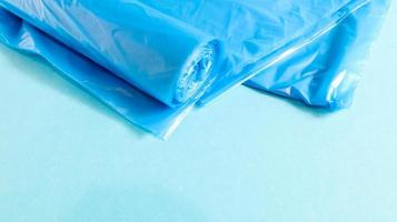 One roll of plastic trash bags in blue on a blue background. Bags that are designed to accommodate garbage in them and used at home and placed in various garbage containers. Copy space photo