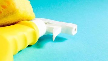 Set of cleaning products on a blue background. Yellow rag and sponge, cleaning spray, detergent. House cleaning concept. photo