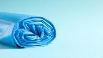 One roll of plastic trash bags in blue on a blue background. Bags that are designed to accommodate garbage in them and used at home and placed in various garbage containers. Copy space photo