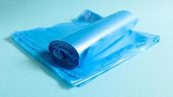 One roll of plastic garbage bags in blue on a blue background. Bags that are designed to accommodate garbage in them and used at home and placed in various garbage containers. photo