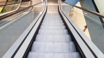 Escalator in the mall. Abstract silver escalator in the interior of the shopping center. Concrete wall background. Transport concept. photo