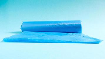 One roll of plastic garbage bags in blue on a blue background. Bags that are designed to accommodate garbage in them and used at home and placed in various garbage containers. photo