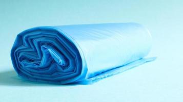 One roll of plastic garbage bags in blue on a blue background. Bags that are designed to accommodate garbage in them and used at home and placed in various garbage containers. photo