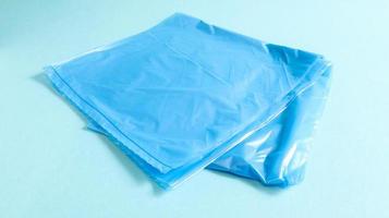 One torn plastic garbage bag in blue on a blue background. A bag that is designed to accommodate garbage in it and is used at home and placed in various garbage containers. photo