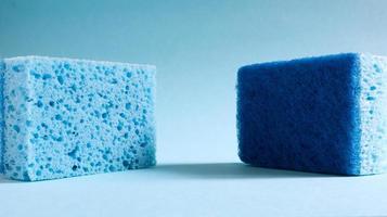 Two blue sponges used for washing and erasing dirt used by housewives in everyday life. They are made of porous material such as foam. Detergent retention, which allows you to spend it economically photo