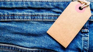 jeans de primer plano con etiqueta de precio blanco de cartón en blanco para su texto. etiqueta la maqueta blanca en los jeans azules. espacio de copia vacío. fondo, concepto de vacaciones. viernes negro foto