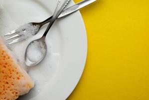 Cleaning sponge on a white plate on a yellow background photo