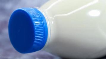 A plastic bottle with a blue cap of fresh regular milk on a dark gray marbled or concrete background. Close-up front view. World milk day concept. Nutrient fluid. photo