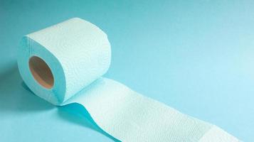 Blue roll of modern toilet paper on a blue background. A paper product on a cardboard sleeve, used for sanitary purposes from cellulose with cutouts for easy tearing. Embossed drawing. copy space. photo