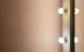 Modern new flat pink wall with two light bulbs from a large floor mirror for makeup and full-length shopping. Abstract modern trendy texture background. Copy space for your text. photo
