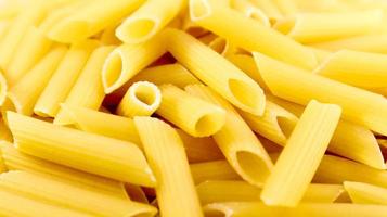 Penne Rigate Raw Pasta is a short pasta with oblique cuts and a ribbed surface. Traditional Italian pasta. Pasta background. Italian food ingredient top view. photo