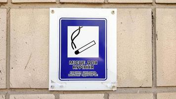 etiqueta con la imagen de un cigarrillo en la ciudad con texto en ucraniano. designación de una zona de fumadores. señales de fumadores, áreas restringidas para fumadores. advirtiendo que fumar es perjudicial para la salud. foto