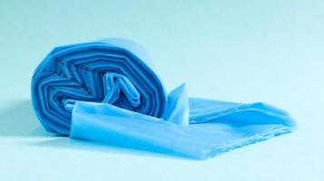 One roll of plastic garbage bags in blue on a blue background. Bags that are designed to accommodate garbage in them and used at home and placed in various garbage containers. photo