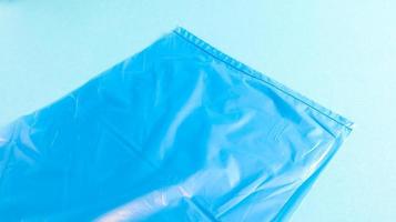 One torn plastic garbage bag in blue on a blue background. A bag that is designed to accommodate garbage in it and is used at home and placed in various garbage containers. photo