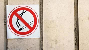 etiquete el letrero redondo de no fumar en la ciudad. letreros de no fumadores que rastrean las paredes de todas las áreas para limitar el área de fumadores. cartel rojo y negro con un fondo de piedra gris texturizado - no fumar foto