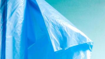 One roll of plastic garbage bags in blue on a blue background. Bags that are designed to accommodate garbage in them and used at home and placed in various garbage containers. photo