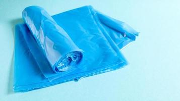 One roll of plastic garbage bags in blue on a blue background. Bags that are designed to accommodate garbage in them and used at home and placed in various garbage containers. photo