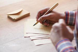 rear view of man writing letter on table photo