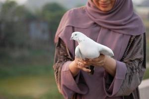 young girl holding pigeon birds in nature in afternoon photo