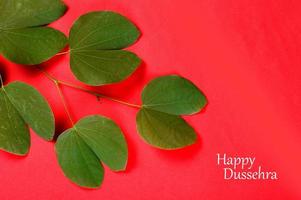 Indian Festival Dussehra, showing golden leaf on red background. Greeting card. photo