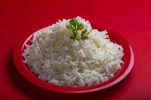 Cooked plain white basmati rice in a red plate on red background photo