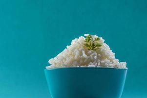 Cooked plain white basmati rice with corriander in a blue bowl on blue background photo