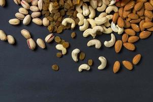 Healthy Mix Dry Fruits and Nuts on dark background. Almonds, Pistachio, Cashews, Raisins photo