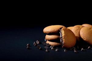 Biscuits filled with chocolate cream. Chocolate cream cookies. brown chocolate biscuits with cream filling on black background. photo