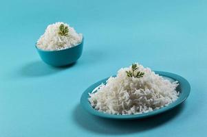 Cooked plain white basmati rice in a blue plate and bowl on blue background photo