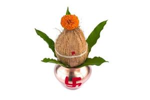 kalash de cobre con hoja de coco y mango con decoración floral sobre fondo blanco. esencial en puja hindú. foto