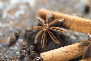 Palitos de canela, estrellas de anís y granos de pimienta negra sobre fondo de textura foto