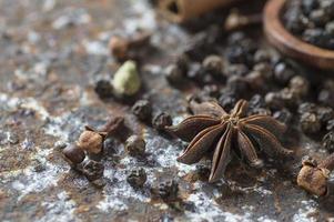 especias y hierbas. ingredientes de la comida y la cocina. palitos de canela, estrellas de anís, pimienta negra y cardamomo sobre un fondo texturizado. foto