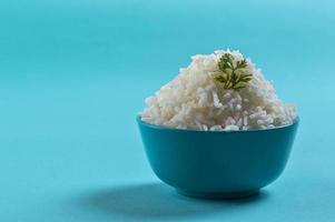 Cooked plain white basmati rice with corriander in a blue bowl on blue background photo